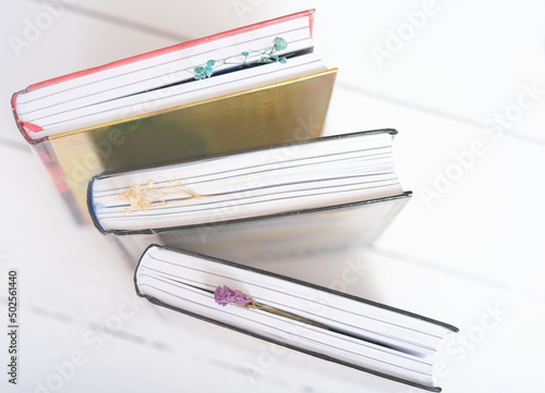  hardcovered books with dry flower bookmarks on a table. Bookshop background. reading and education, study and learning concept.