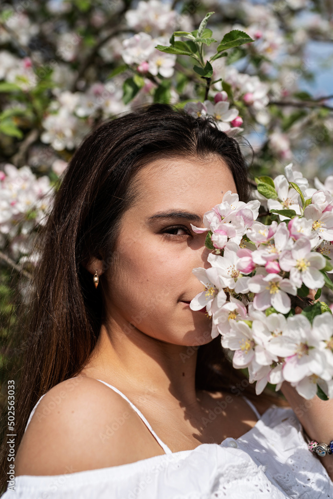Fototapeta premium Young caucasian woman enjoying the flowering of an apple trees
