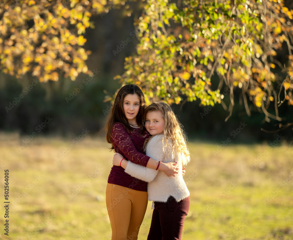 Fototapeta premium Portrait of two charming kind cheerful girls wearing casual hugging good mood