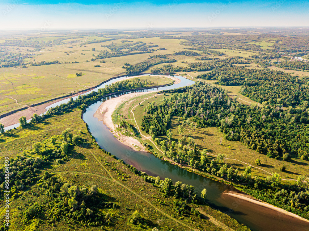 Aerial top view of a peaceful river valley among green plain. Summer scene and eco environment.