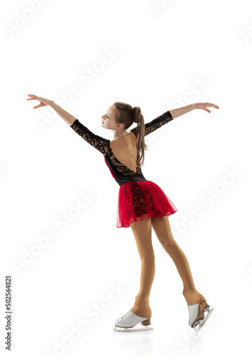 Portrait of little flexible girl, figure skater wearing stage attire posing isolated on white studio background. Concept of movement, sport, beauty.