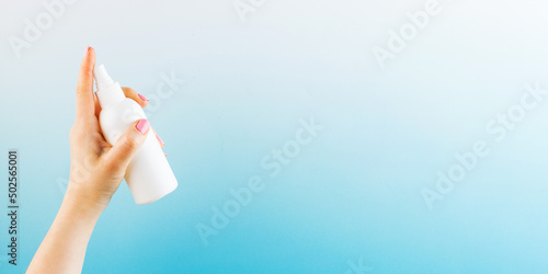 Schilderij op canvas Lady hand sprays air refresher from blank bottle on blue background close view