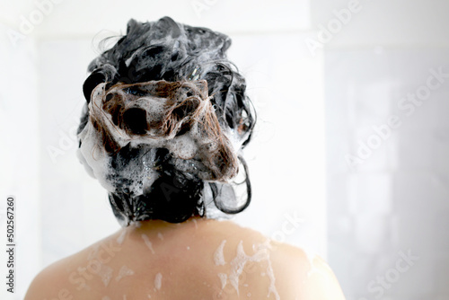 Woman is washing her hair with shampoo