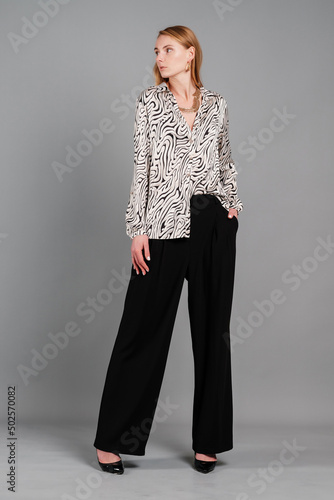 Stylish female in a blouse and trousers. Studio woman portrait.