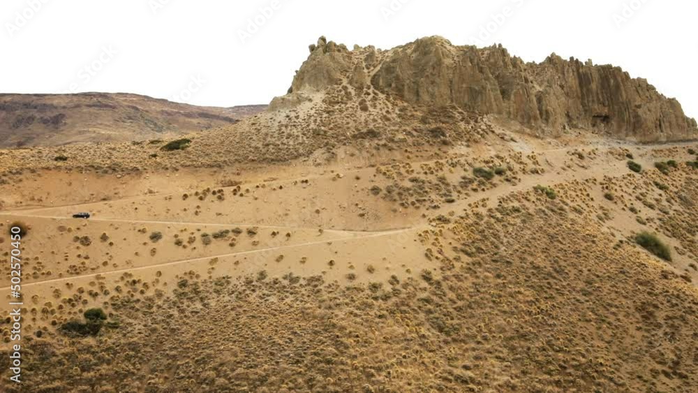 Traveling along the desert. View of a 4x4 truck driving along the desert dirt road into the arid mountains. Traveling along the desert. View of a 4x4 truck driving along the desert dirt road into the arid mountains.