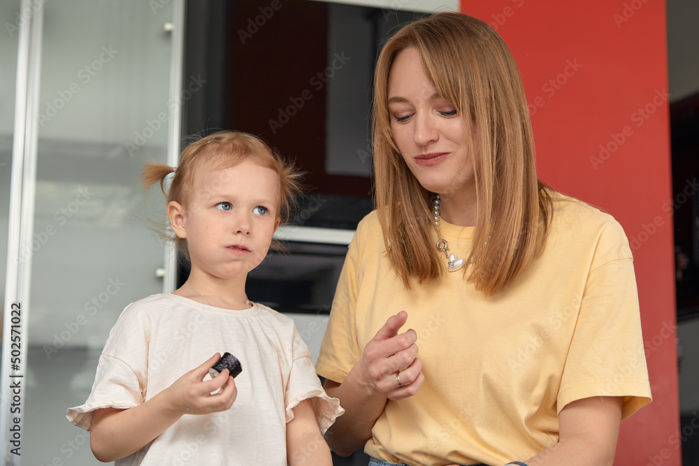 Beautiful caucasian mom and daughter eating rolls and sushi at family lunch at home. Delivery food. Traditional japanese food. Beautiful caucasian mom and daughter eating rolls and sushi at family lunch at home. Delivery food. Traditional japanese food.