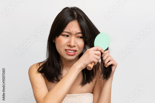 Portrait of unhappy Asian lady brushing her hair