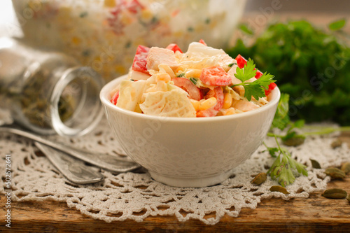 Beijing cabbage and sweet pepper salad in a white plate. Wooden background.