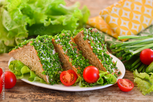 Appetizing sandwich with herbs and tomatoes. Wooden background.