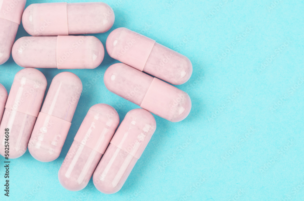 Pink capsule pills on blue background. Pink capsule pills on blue background.