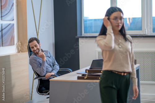 Pleased young boss staring after his secretary