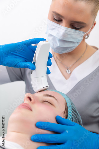 Young woman receiving electric galvanic anti-aging face spa massage at beauty salon.