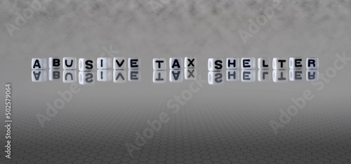 abusive tax shelter word or concept represented by black and white letter cubes on a grey horizon background stretching to infinity photo