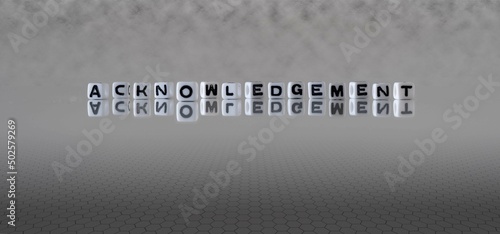 acknowledgement word or concept represented by black and white letter cubes on a grey horizon background stretching to infinity photo