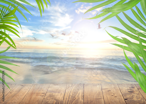 Fototapeta Naklejka Na Ścianę i Meble -  Empty Wooden Planks With Blur Sea and sun On background-Coconut Palm leafs.