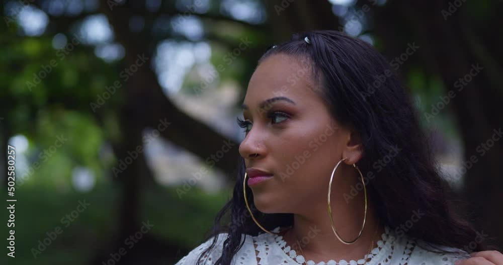Amazing facial close up of a young female with a nose ring and hoop earings at a park Amazing facial close up of a young female with a nose ring and hoop earings at a park