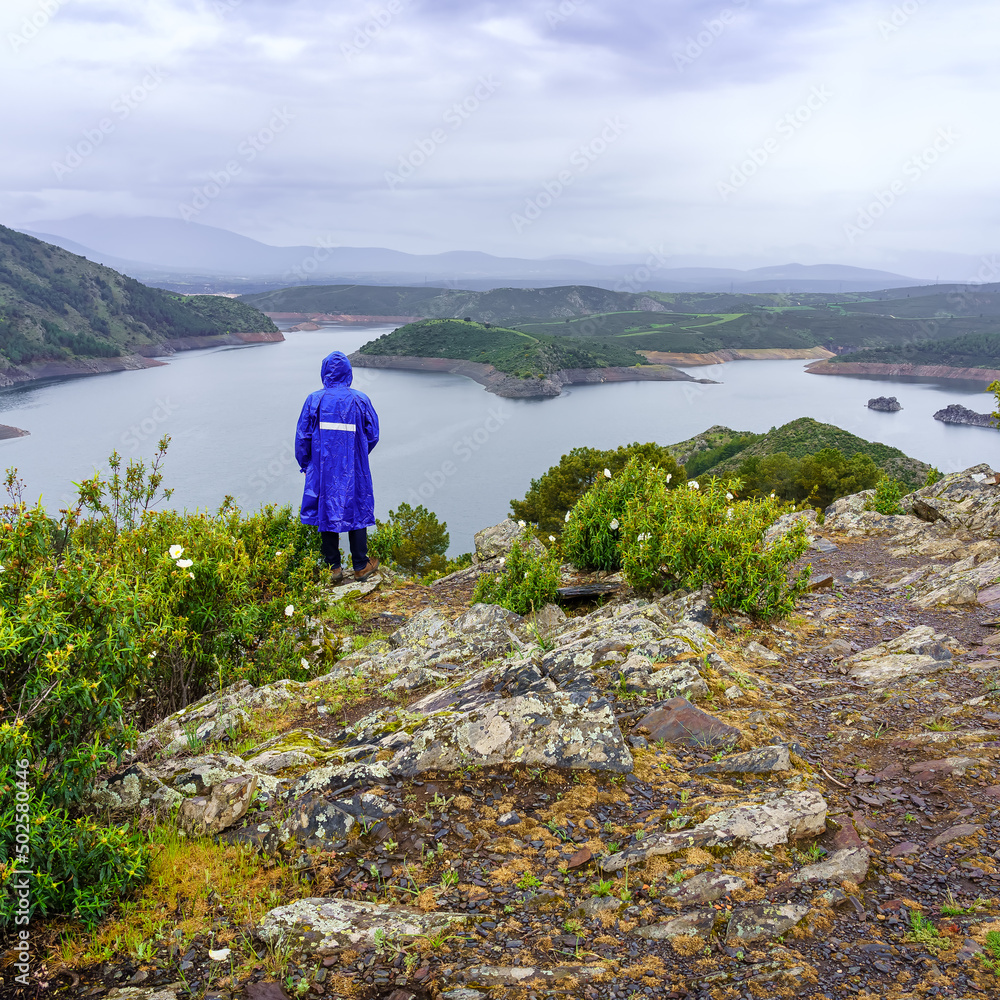 Fototapeta premium Man contemplating the mountainous landscape on a rainy day.