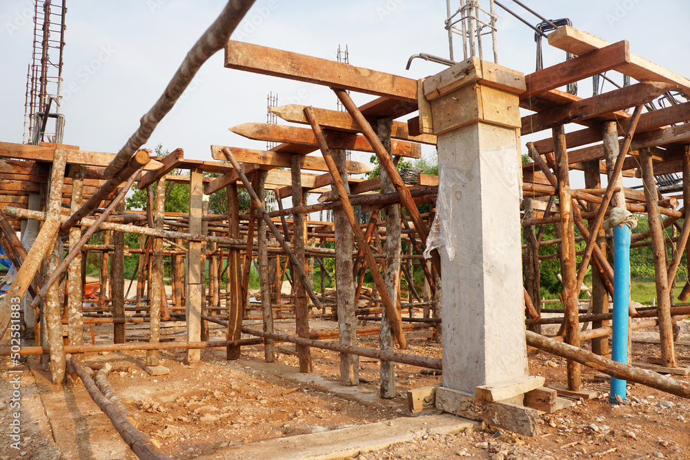 Temporary poles and wooden scaffolding support the concrete beam framework at the house construction site.