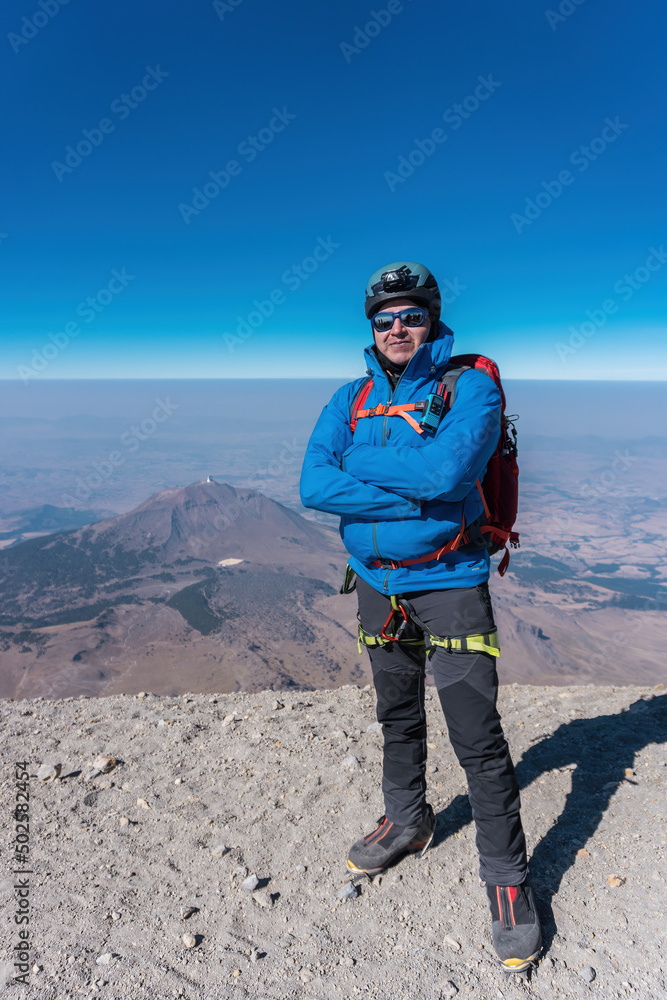 man on top of the pico de orizaba volcano and in the background the sierra negra volcano