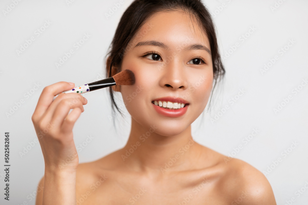 Fototapeta premium Portrait of beautiful Asian woman with makeup brush