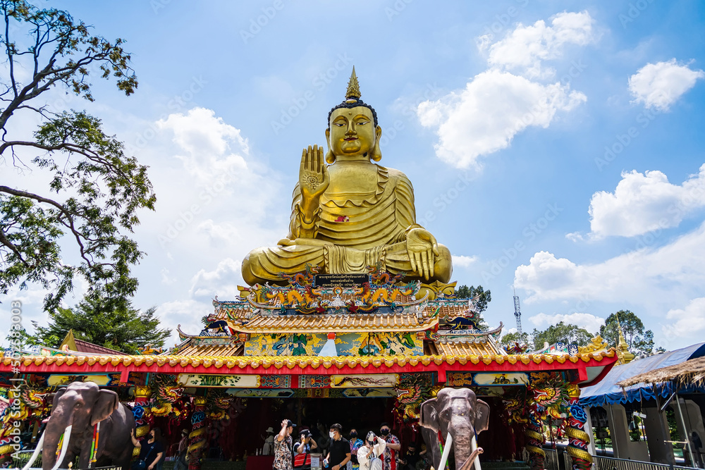 Fototapeta premium Nakhon Nayok, Thailand - April, 24, 2022 : Golden buddha statue of Maniwong Temple at Nakhon Nayok, Thailand.