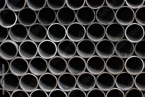 Maetallic pipes of the same diameter are neatly stacked. View of pipes from the front. Background for the supplier of metal products.