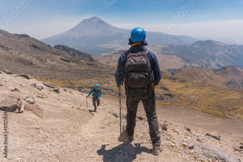 Photograph of adventurous backpacker standing on mountain peak.