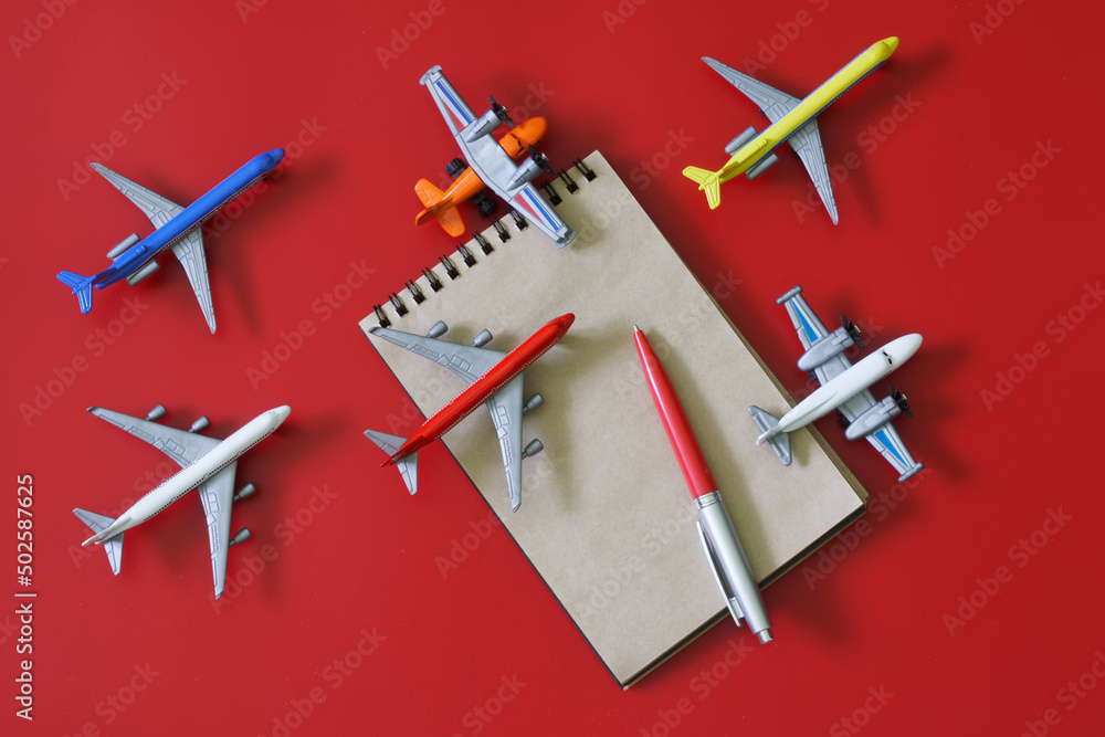 Notepad and fountain pen next to many toy models of passenger planes