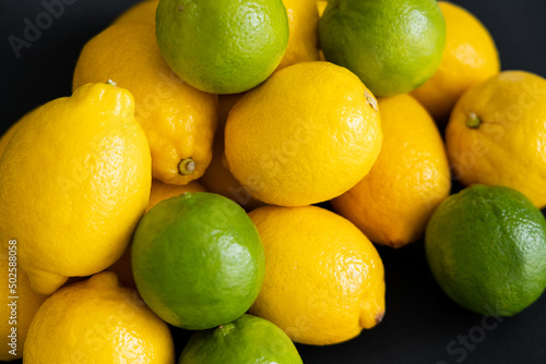 Fototapeta Naklejka Na Ścianę i Meble -  High angle view of organic lemons and limes on black background