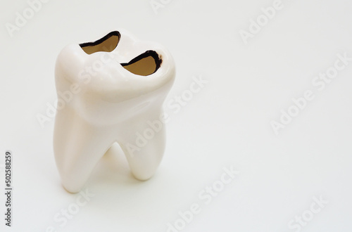 artificial white glass tooth ashtray with holes in the shape of caries close-up