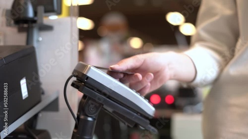 Woman's hand, payment by bank card at the terminal at the cash register in the supermarket