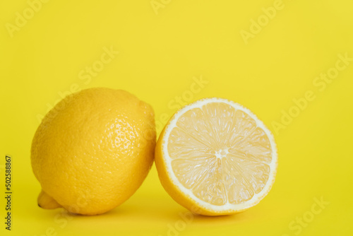 Close up view of half and whole lemon on yellow background