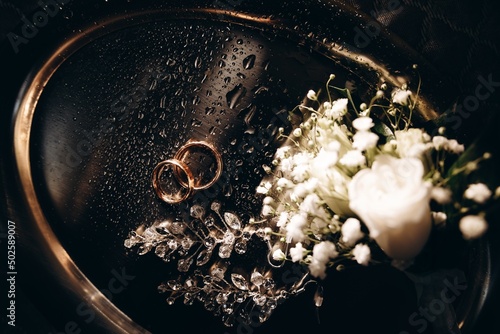 Macro photography wedding rings and earrings in water drops, engagement rings symbolizing love, with gold shades.