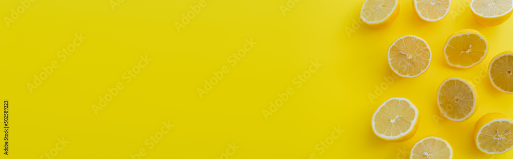 Top view of cut lemons on yellow surface with copy space, banner