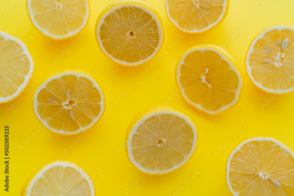 Top view of halves of fresh lemons on yellow surface