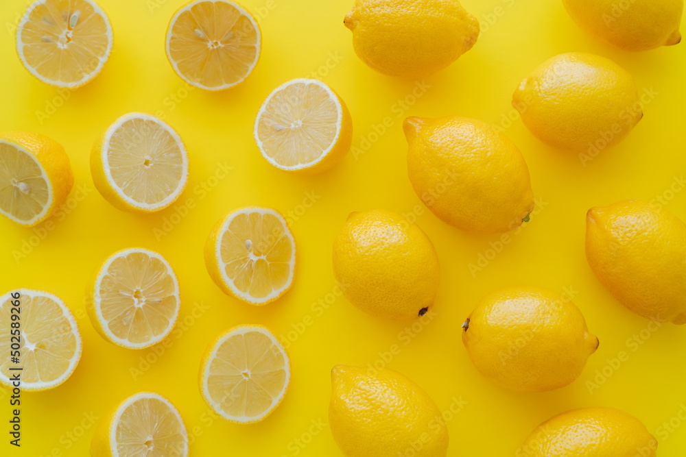 Flat lay with halves and whole lemons on yellow surface