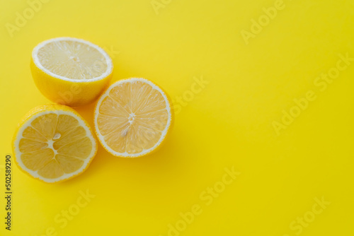 Top view of halves of lemons on yellow background