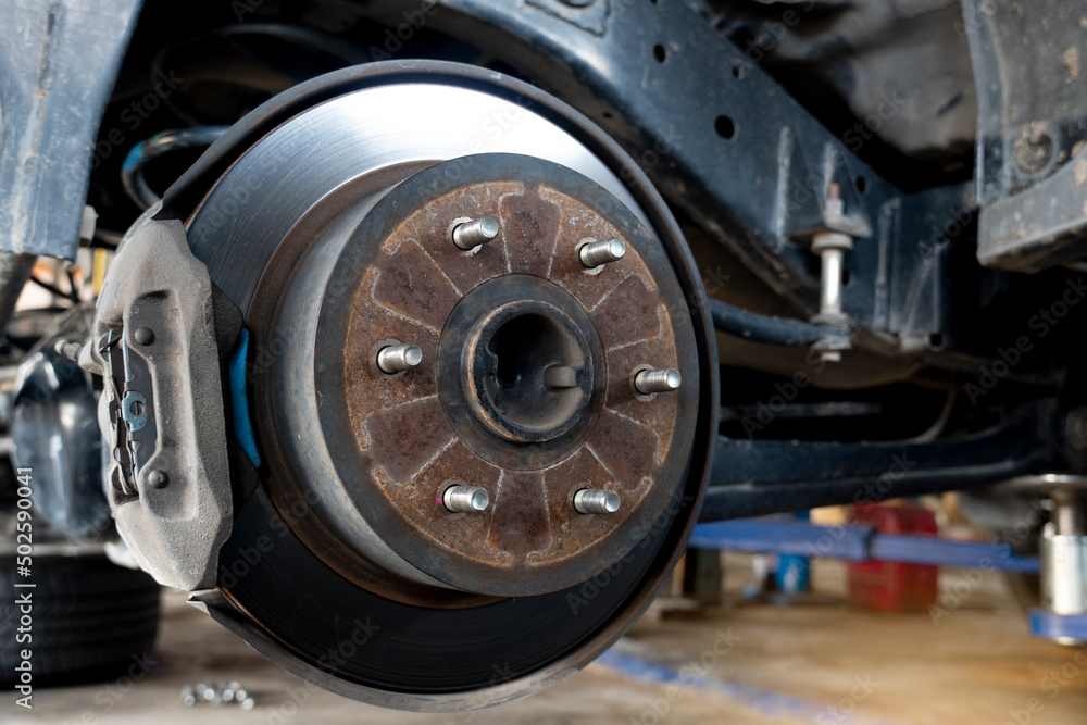 Maintenance background of car's suspension with the rear wheels removed reveals disc brakes. Maintenance background of car's suspension with the rear wheels removed reveals disc brakes.