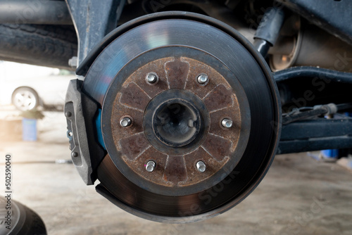 Maintenance background of car s suspension with the rear wheels removed reveals disc brakes.