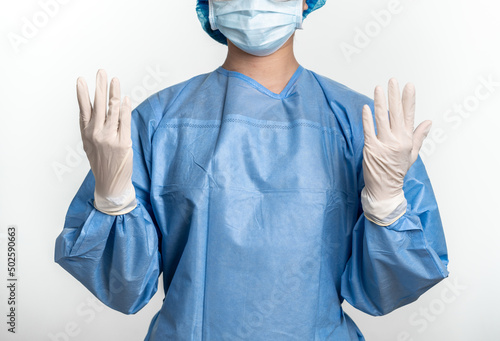 Female doctor or nurse with protective suit and mask is wearing medical gloves 