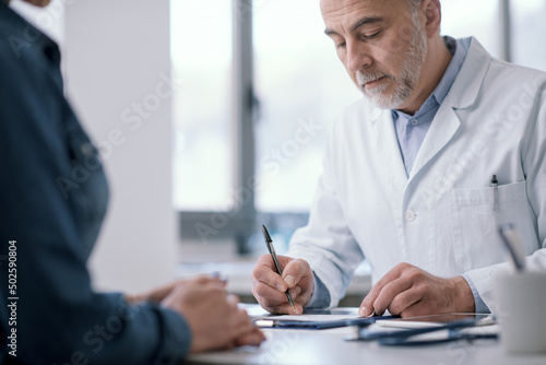 Doctor writing a medical prescription for his patient