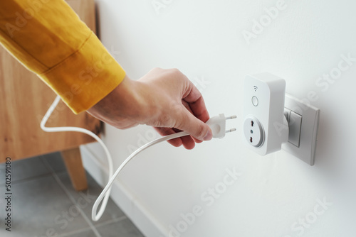 Foto Woman plugging a device into a smart plug