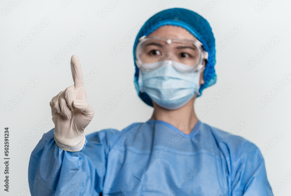 Female doctor or nurse wearing protective suit is pointing the blank above with single finger Female doctor or nurse wearing protective suit is pointing the blank above with single finger