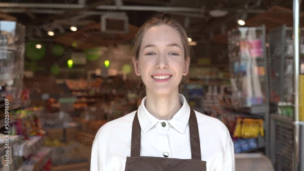 The girl supermarket cashier smiles for the camera. High quality FullHD footage The girl supermarket cashier smiles for the camera. High quality FullHD footage