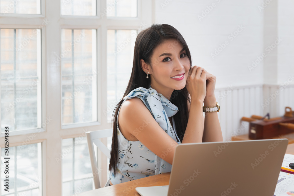 Portrait of smiling pretty business woman sitting at wooden desk in office and looking at camera. Portrait of smiling pretty business woman sitting at wooden desk in office and looking at camera.