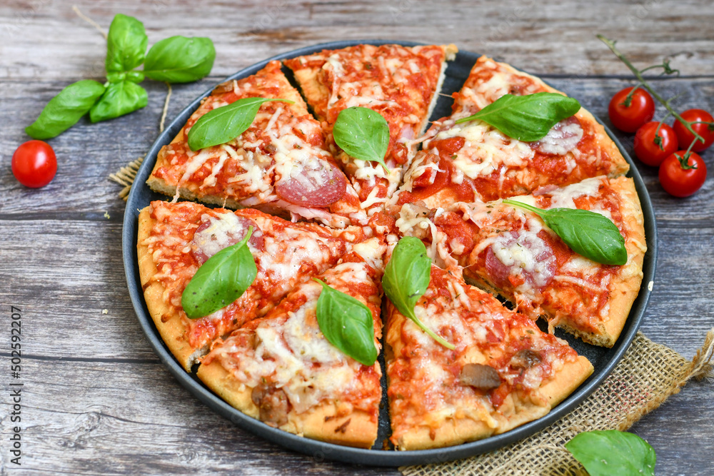 Close up of classic Italian Pizza with Ham and salami . Fresh basil,tomato sauce ,mozzarella cheese , mushrooms and green peppers Close up of classic Italian Pizza with Ham and salami . Fresh basil,tomato sauce ,mozzarella cheese , mushrooms and green peppers