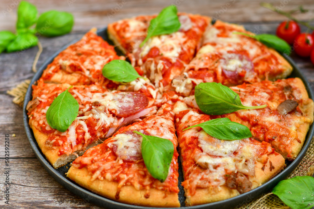 Close up of classic Italian Pizza with Ham and salami . Fresh basil,tomato sauce ,mozzarella cheese , mushrooms and green peppers Close up of classic Italian Pizza with Ham and salami . Fresh basil,tomato sauce ,mozzarella cheese , mushrooms and green peppers