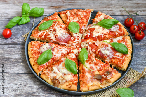  Close up of classic Italian Pizza with Ham and salami . Fresh basil,tomato sauce ,mozzarella cheese , mushrooms and green peppers