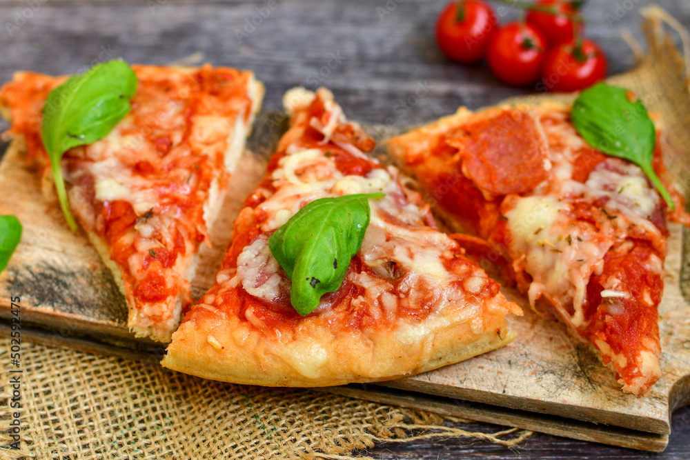 Close up of classic Italian Pizza with Ham and salami . Fresh basil,tomato sauce ,mozzarella cheese , mushrooms and green peppers Close up of classic Italian Pizza with Ham and salami . Fresh basil,tomato sauce ,mozzarella cheese , mushrooms and green peppers