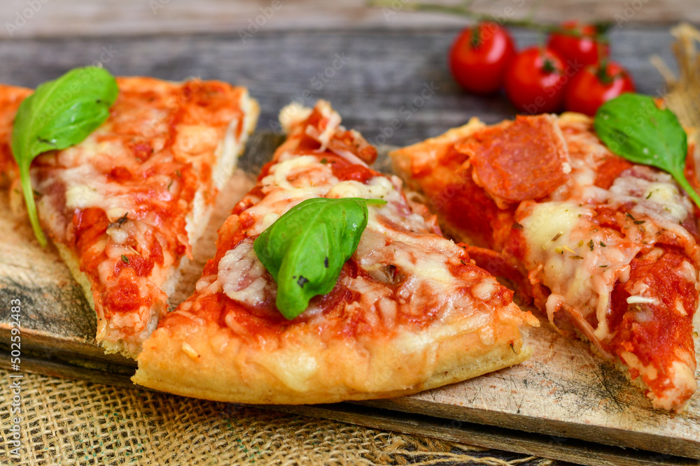 Close up of classic Italian Pizza with Ham and salami . Fresh basil,tomato sauce ,mozzarella cheese , mushrooms and green peppers Close up of classic Italian Pizza with Ham and salami . Fresh basil,tomato sauce ,mozzarella cheese , mushrooms and green peppers